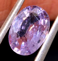 an oval shaped purple diamond being held by two tongs