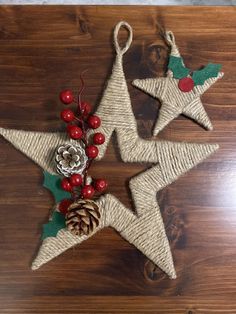 two christmas stars with holly berries and pine cones on them are hanging from twine