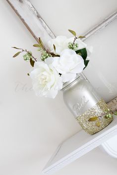 white flowers are in a mason jar on a shelf