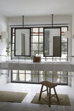 a marble counter top in a white room with mirrors on the wall and stools