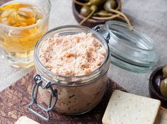 a glass jar filled with food sitting on top of a table next to crackers