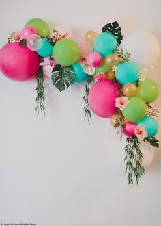 balloons and greenery are arranged in the shape of a letter m on a white wall