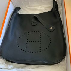 This Is An Authentic Hermes Evelyne Bag Size 40 In Never Worn Condition. The Size Is Amazing For Everyday Use And Can Carry A Laptop Or Ipad In Addition To Other Items. Comes With A Cross Body Strap (Or Shoulder If You Shorten It). Hardware Is Palladium. Great For Traveling Too. Comes With The Original Box And Dust Bag. Bought At Hermes / Bev Hills - July 2022. *Please Note That Due To How It Was Stored, There Are Identical Tiny White Lines In The Opposite Corners. They Are Barely Detectable. Pl Birkin Bag Price, Hermes Travel Bag, Hermes Evelyne Iii, Hermes Evelyn Bag, Hermes Kelly Bag, Hermes Kelly 28, Kelly Bag, Canvas Crossbody Bag, Black Leather Crossbody Bag