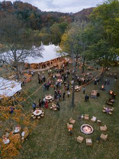 an aerial view of a group of people sitting around a fire pit in the middle of a field