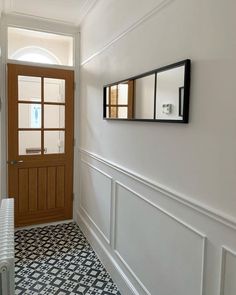 Astounding style combinations exist in this hallway, where beautifully patterned tiles meet a wooden interior door and white millwork. Gray and white tiles draw attention to the flooring, accentuating their funky flair. The walls exude elegance thanks to thin wainscoting and a stylish mirror...   Image: newhome_oldhouse_