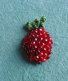 a red beaded pomegranate sitting on top of a blue cloth