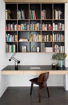 a desk with a chair and bookshelf behind it