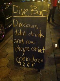 a chalkboard sign on the side of a sidewalk that says, dive bar dinosaurs didn't drink and now they are extinct