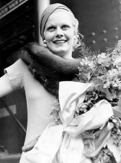 an old photo of a woman in a dress with flowers on her head and scarf around her neck