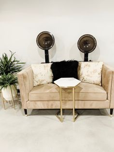 a beige couch sitting next to a table with two fans on it's head