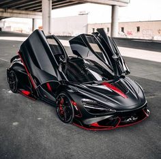 the black and red sports car is parked in an empty parking lot with its doors open