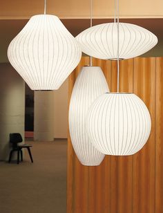 three white lamps hanging from the ceiling in an office building with wood paneled walls