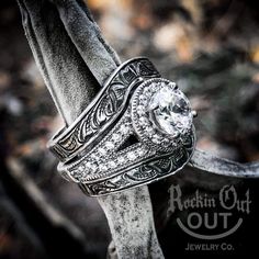 an antique style diamond ring sitting on top of a tree branch