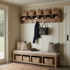 a wooden bench with baskets on it in front of a white wall and open doors