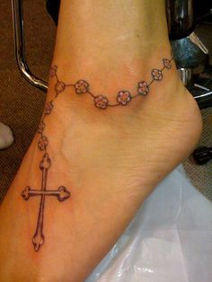 a woman's foot with a rosary tattoo on it