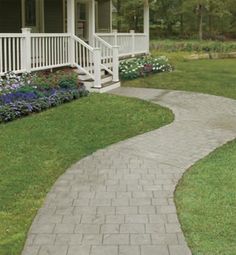 a walkway leading to a house with flowers in the front yard