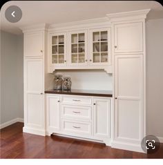 an empty kitchen with white cabinets and wood flooring in front of the counter top