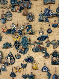 an assortment of blue and yellow brooches sitting on top of a sandy surface