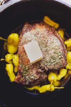 a piece of meat in a pot with yellow peppers