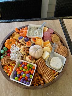 a wooden platter filled with lots of different types of candy and crackers on top of a table