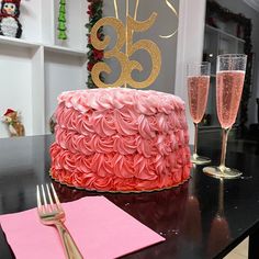 a cake with pink frosting and gold numbers on it next to two glasses of champagne