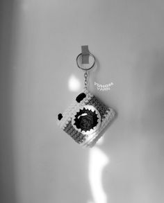 a crocheted keychain hanging on the wall with a black and white photo