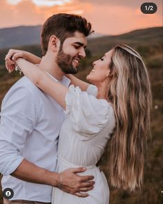 a man and woman embracing each other while the sun is setting