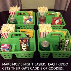 four green baskets filled with movie snacks and sodas on top of a black table