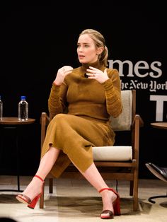 a woman sitting in a chair with her hands on her hips and talking to someone