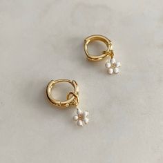 The Daisy Hoops are a necessary addition to your ear stack! A classic huggie hoop with a sweet Daisy dangle.  The Daisy hoops will be your new favourite earrings to brighten up your look! Wear the hoop with the Daisy to update your look or without for the simple classic look, we love options! Finished in high-polish 18k gold filled. 12mm huggie hoop with a 10x5mm Daisy drop. Trendy White Huggie Hoop Earrings, Dainty White Huggie Dangle Earrings, Dainty White Dangle Huggie Earrings, Trendy Clip-on Dangle Hoop Earrings, Trendy Small Hoop Earrings With Dangling Charms, White Hypoallergenic Dangle Huggie Earrings, White Dangle Clip-on Hoop Earrings, Trendy Dangle Clip-on Hoop Earrings, White Small Hoop Huggie Earring