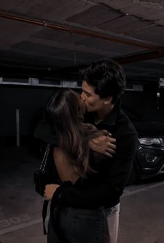 a man and woman kissing in an empty parking garage