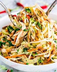 a white bowl filled with coleslaw and chicken salad on top of a table