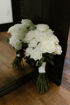 a bouquet of white flowers sitting on top of a wooden floor next to a mirror