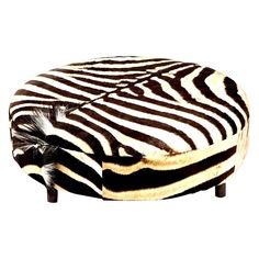 a zebra print ottoman with wooden legs and an animal hide covering on it's back