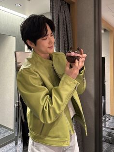 a man holding a chocolate donut in his hand while standing next to a mirror