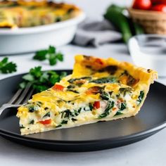 a slice of quiche on a black plate with a fork next to the casserole