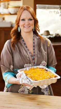 a woman holding a casserole dish in her hands and smiling at the camera