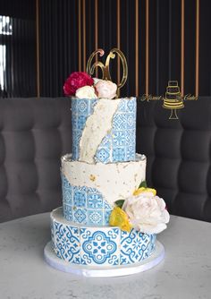 a three tiered cake with blue and white designs on the top is decorated with flowers