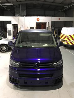 a blue car parked in a garage next to other cars and an ambulance behind it