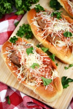 three hot dogs covered in cheese and parmesan on a cutting board with parsley