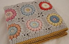 a crocheted blanket with multicolored flowers on it