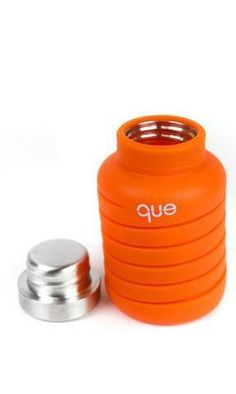 an orange cup with the lid open next to a metal container and two other items