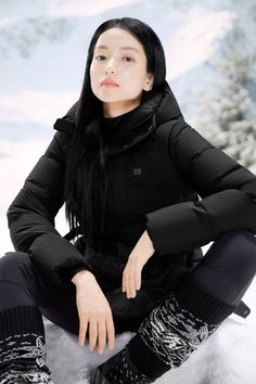 a woman sitting in the snow with her hands on her knees, wearing black clothes