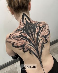 the back of a woman's upper body with black ink and white flowers on it