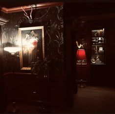 a dark room with a painting on the wall and a red lamp in front of it