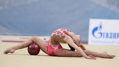 a woman is laying on the ground with her arms around her head while holding onto a bowling ball