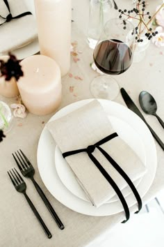 the table is set with black and white napkins, silverware, and candles