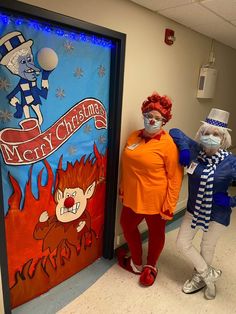 two people in costumes standing next to each other near a door with decorations on it