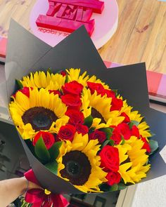 a bouquet of sunflowers and roses is being held