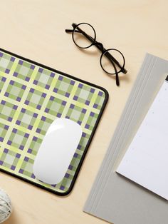 a computer mouse pad sitting on top of a desk next to a pair of glasses